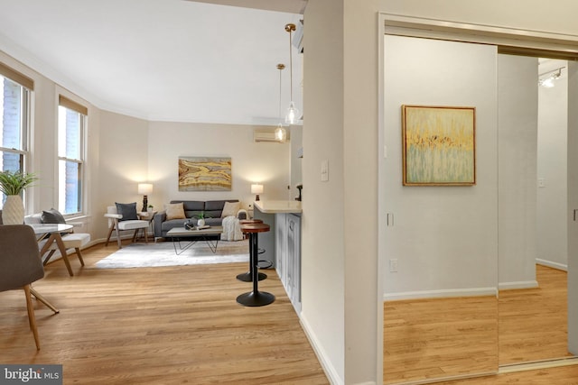 interior space featuring a wall mounted AC, light wood-type flooring, and baseboards