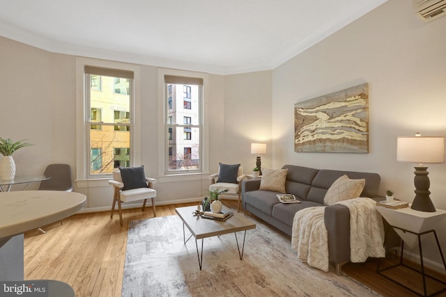 living room with a wall mounted air conditioner, crown molding, baseboards, and wood finished floors