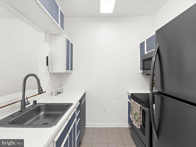 kitchen with light countertops, stainless steel microwave, freestanding refrigerator, a sink, and range with electric cooktop