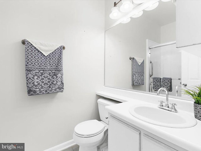 bathroom featuring toilet, a stall shower, vanity, and baseboards