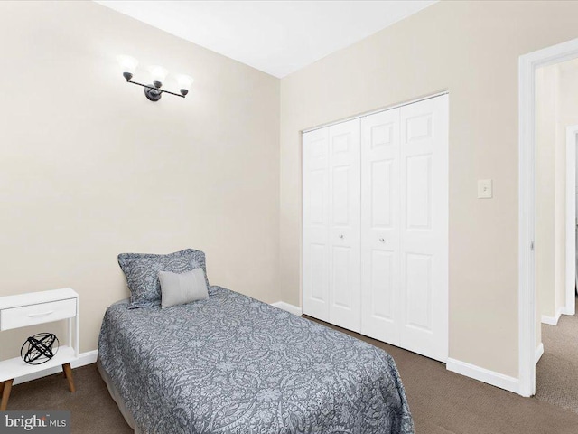 carpeted bedroom with a closet and baseboards