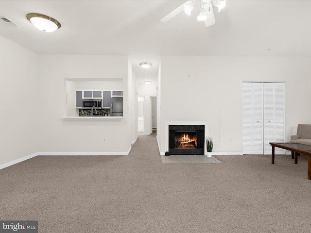 unfurnished living room with a fireplace with flush hearth, baseboards, visible vents, and carpet flooring