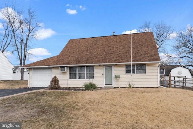 view of front of property featuring a garage, a shingled roof, aphalt driveway, a wall mounted air conditioner, and a front yard