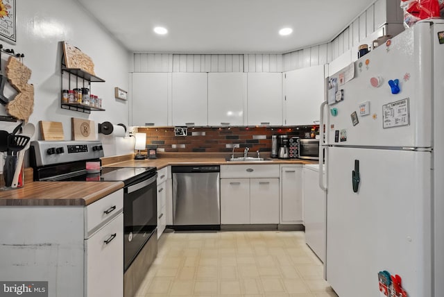 kitchen with white cabinets, stainless steel appliances, light floors, a sink, and recessed lighting