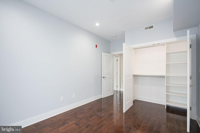 unfurnished bedroom featuring baseboards, a closet, visible vents, and hardwood / wood-style floors