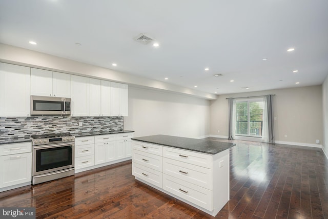 kitchen featuring stainless steel appliances, white cabinetry, visible vents, decorative backsplash, and dark wood-style floors