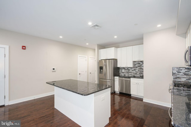 kitchen featuring a sink, backsplash, stainless steel appliances, and dark wood-type flooring