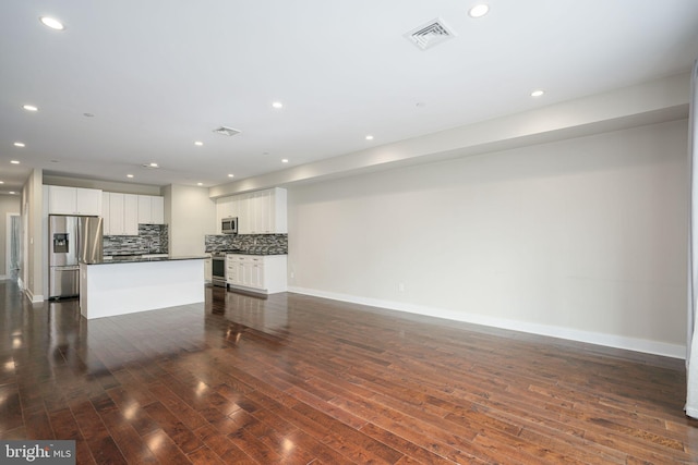 unfurnished living room with dark wood-style floors, baseboards, visible vents, and recessed lighting