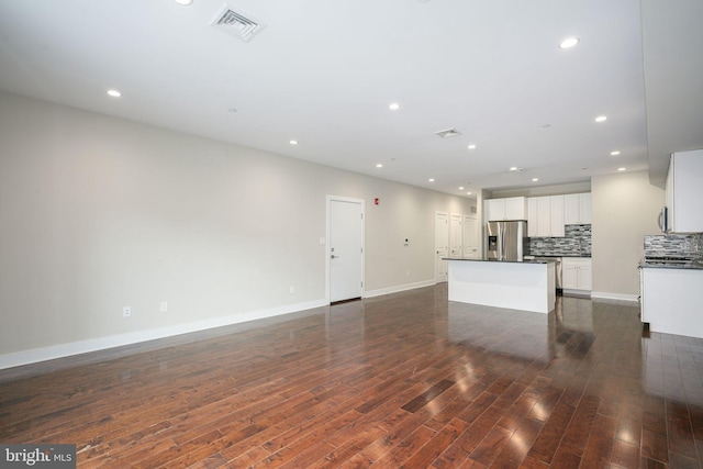 unfurnished living room featuring baseboards, visible vents, dark wood-type flooring, and recessed lighting