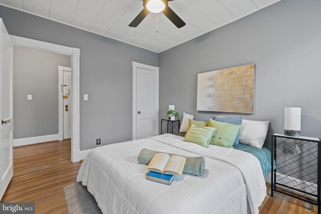 bedroom with ceiling fan, wood finished floors, and baseboards