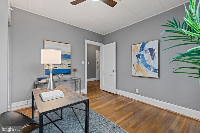 home office with wood-type flooring, a ceiling fan, and baseboards