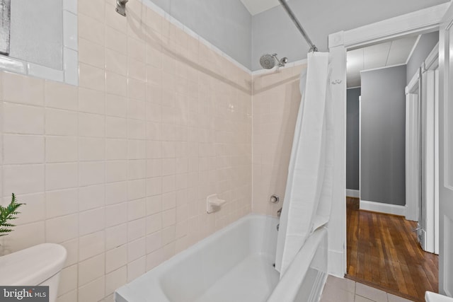 bathroom with tile patterned flooring, shower / bathtub combination with curtain, and toilet