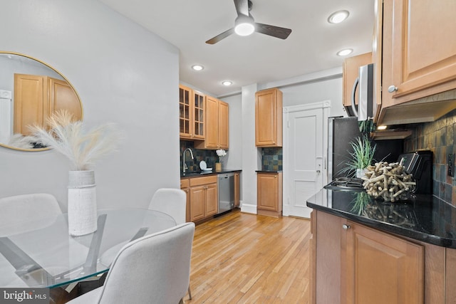 kitchen featuring tasteful backsplash, light wood-style flooring, glass insert cabinets, appliances with stainless steel finishes, and a sink