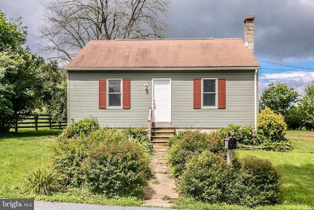 view of front facade featuring a front lawn, a chimney, and fence