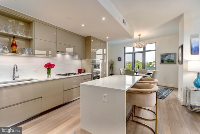 kitchen with backsplash, light wood-style floors, a kitchen island, a sink, and modern cabinets