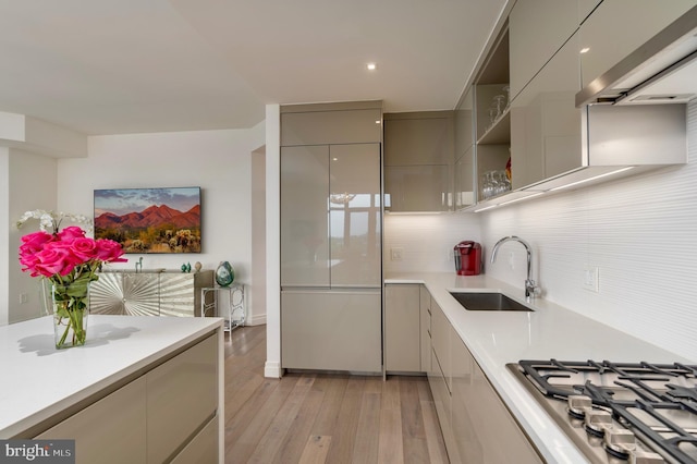 kitchen featuring stainless steel gas cooktop, tasteful backsplash, light countertops, gray cabinetry, and a sink