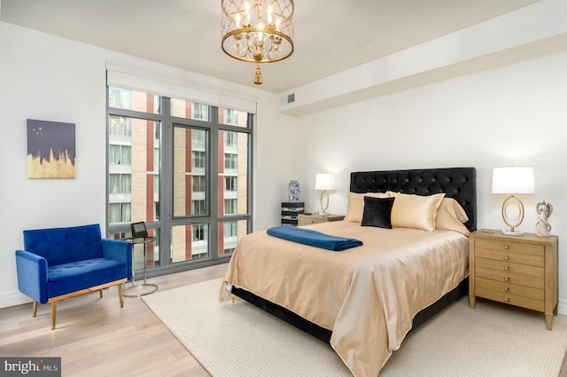 bedroom with light wood-style floors, visible vents, a notable chandelier, and baseboards