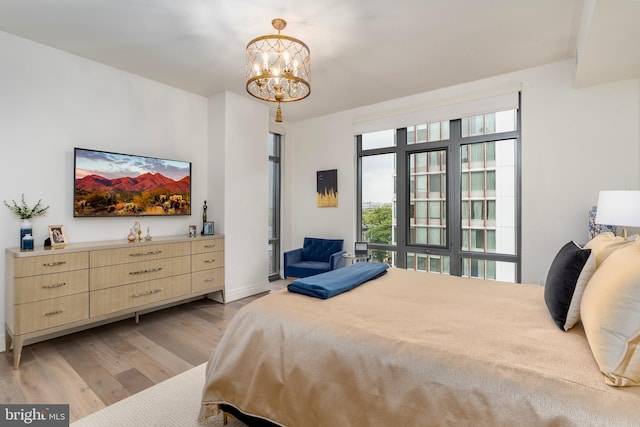 bedroom with a notable chandelier, light wood-style flooring, and baseboards