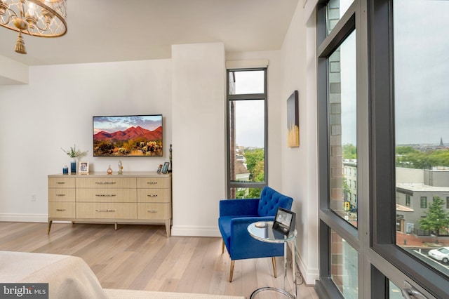 sitting room with a chandelier, baseboards, and light wood-style floors