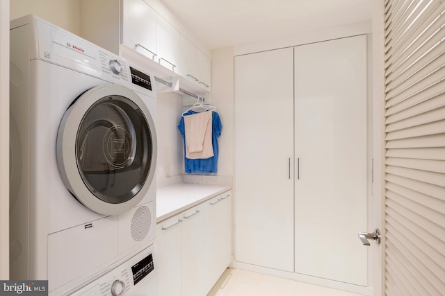 washroom with cabinet space and stacked washing maching and dryer