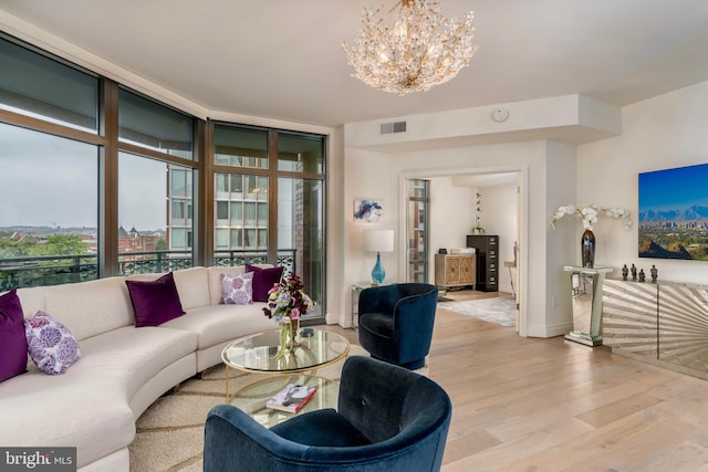 living room with floor to ceiling windows, a notable chandelier, visible vents, light wood-style flooring, and baseboards