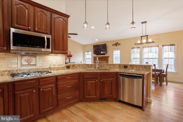 kitchen featuring light stone countertops, appliances with stainless steel finishes, pendant lighting, and a sink