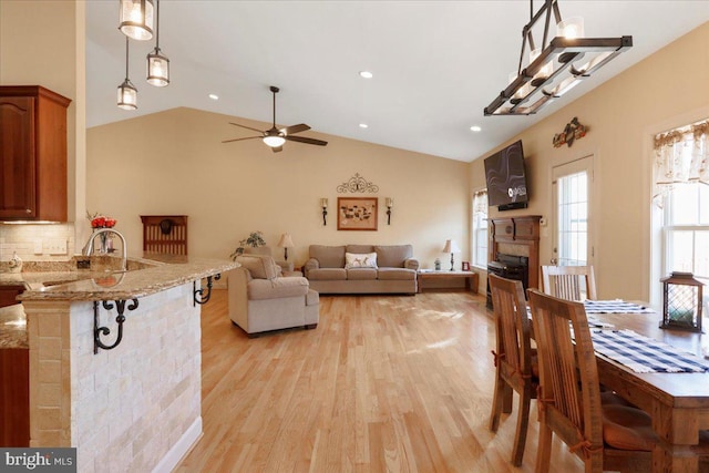 dining space with lofted ceiling, ceiling fan, recessed lighting, a fireplace, and light wood-style floors