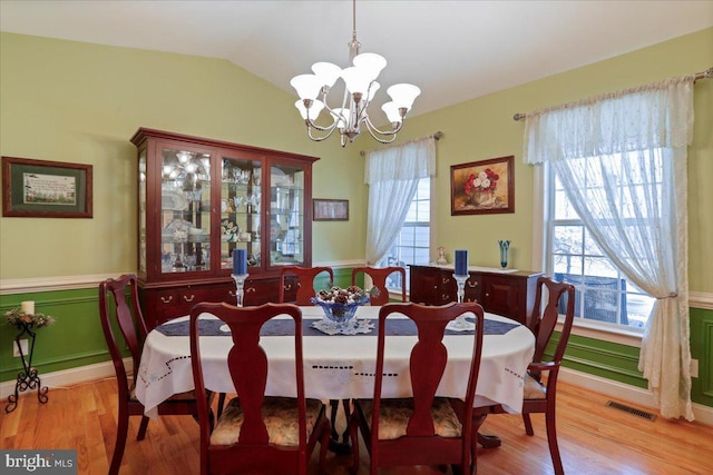 dining area featuring lofted ceiling, wainscoting, visible vents, and light wood-style floors