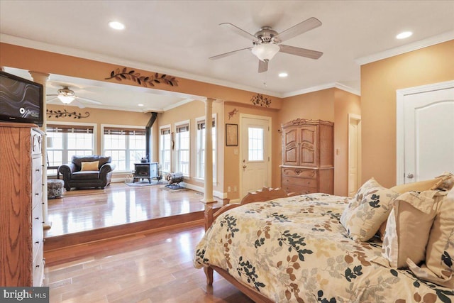 bedroom featuring ornamental molding, recessed lighting, a wood stove, and wood finished floors