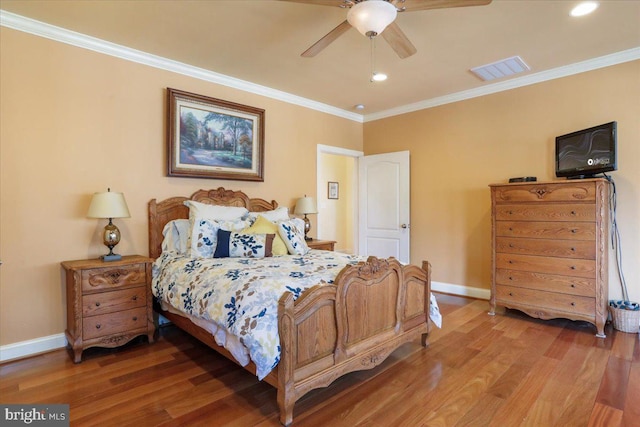 bedroom featuring visible vents, crown molding, baseboards, and wood finished floors