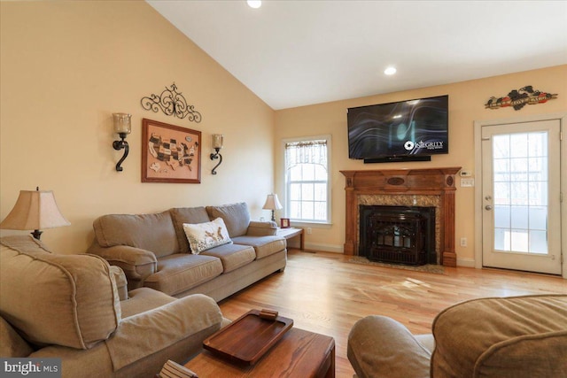 living room featuring recessed lighting, a premium fireplace, wood finished floors, baseboards, and vaulted ceiling