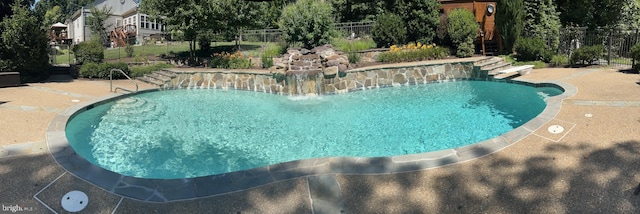 outdoor pool with fence, a patio, and a diving board