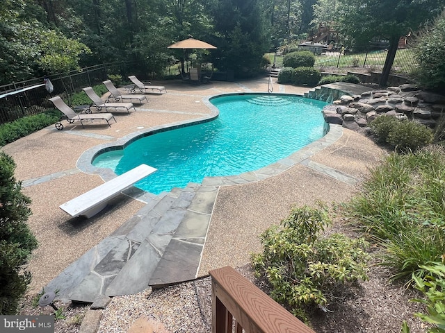 view of swimming pool with a diving board, a patio, fence, and a fenced in pool