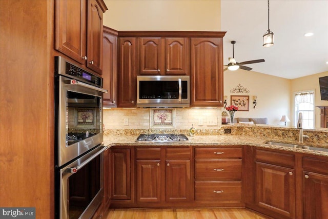 kitchen with a ceiling fan, a sink, light stone countertops, stainless steel appliances, and backsplash