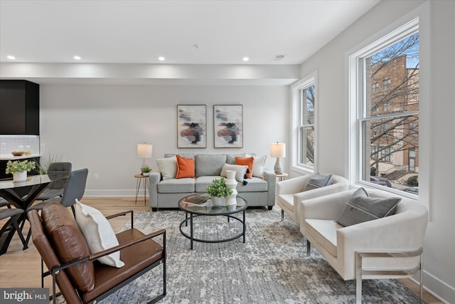 living area with recessed lighting, visible vents, baseboards, and light wood-style flooring