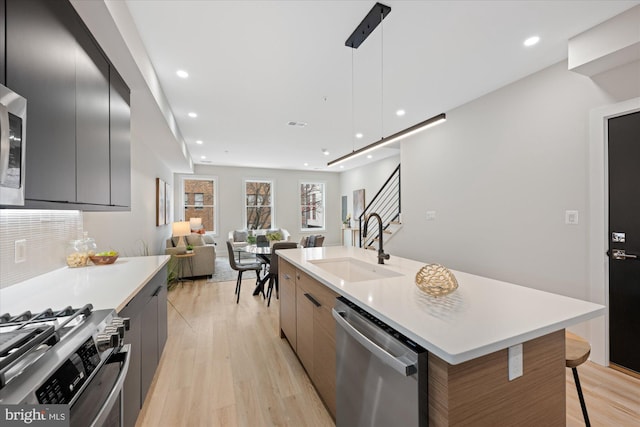 kitchen featuring a breakfast bar area, light wood finished floors, a sink, appliances with stainless steel finishes, and modern cabinets