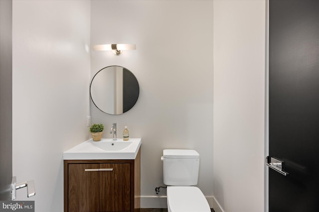 bathroom featuring toilet, vanity, and baseboards