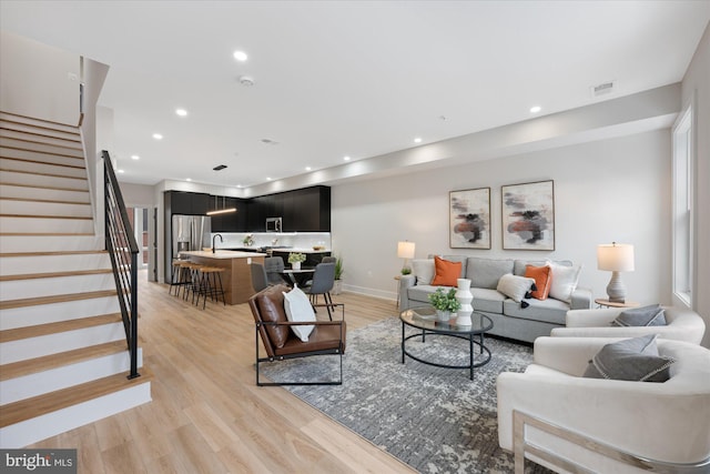 living room with light wood-type flooring, visible vents, recessed lighting, stairway, and baseboards