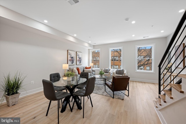 dining space with stairs, baseboards, visible vents, and light wood finished floors