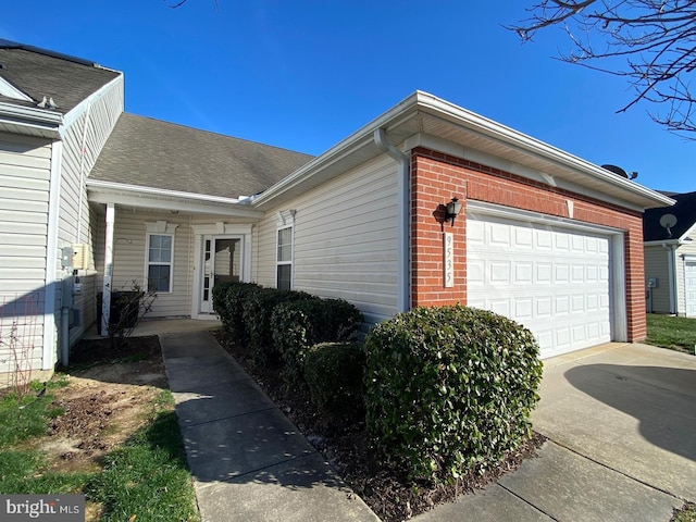 view of side of home featuring concrete driveway, brick siding, and an attached garage