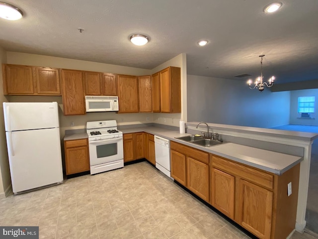 kitchen with a chandelier, a peninsula, white appliances, a sink, and brown cabinets