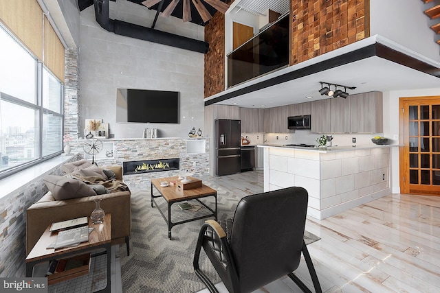 living room featuring light wood-style flooring, a high ceiling, and a fireplace