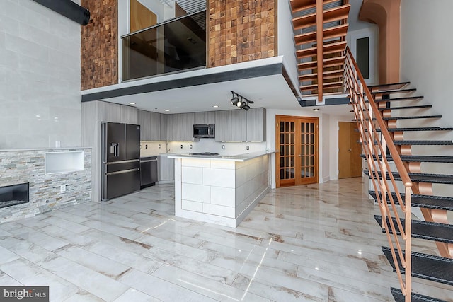 kitchen featuring stainless steel appliances, a high ceiling, modern cabinets, and light countertops