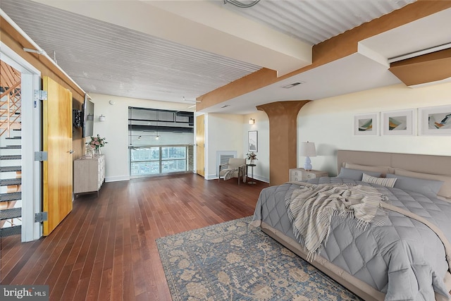 bedroom with beamed ceiling, wood finished floors, visible vents, and baseboards