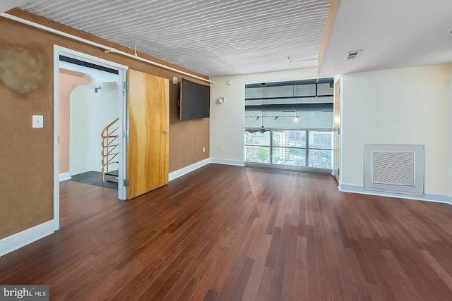 empty room with stairway, visible vents, and dark wood finished floors