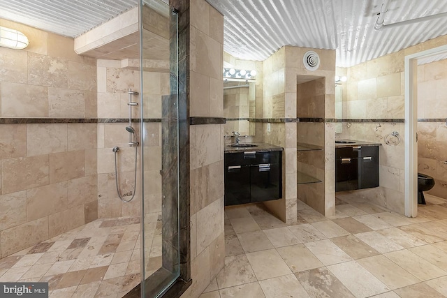 bathroom with tile walls, a shower stall, and vanity