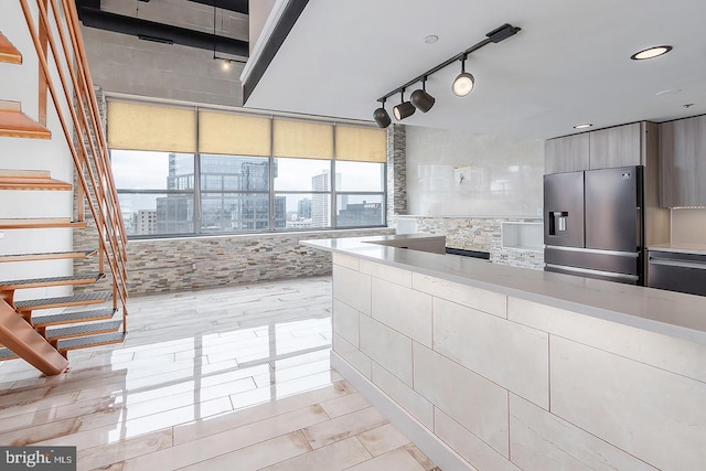 kitchen with a view of city, rail lighting, light countertops, modern cabinets, and stainless steel fridge with ice dispenser