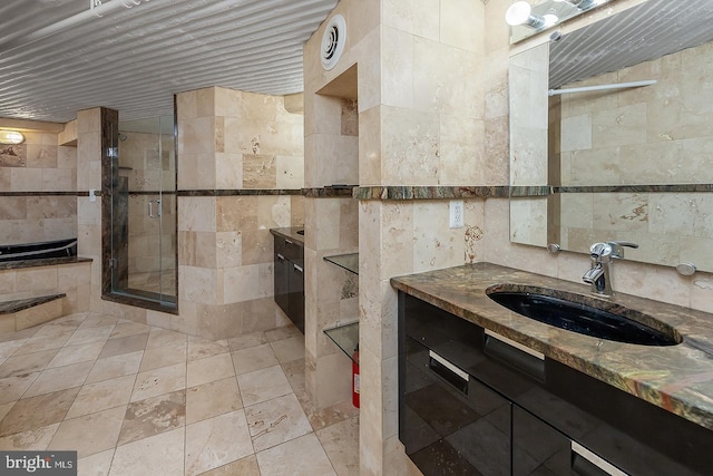 full bathroom with a shower stall, tile walls, and vanity