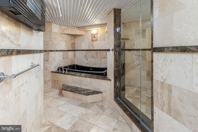 bathroom with a stall shower, tile patterned flooring, a garden tub, and tile walls