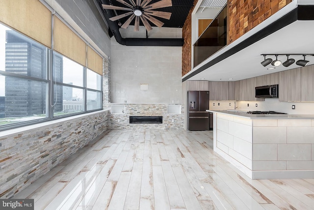 kitchen featuring modern cabinets, fridge with ice dispenser, stainless steel microwave, and light countertops